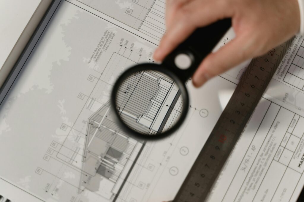 Close-up of magnifying glass over architectural blueprint, representing detailed planning in data project discovery